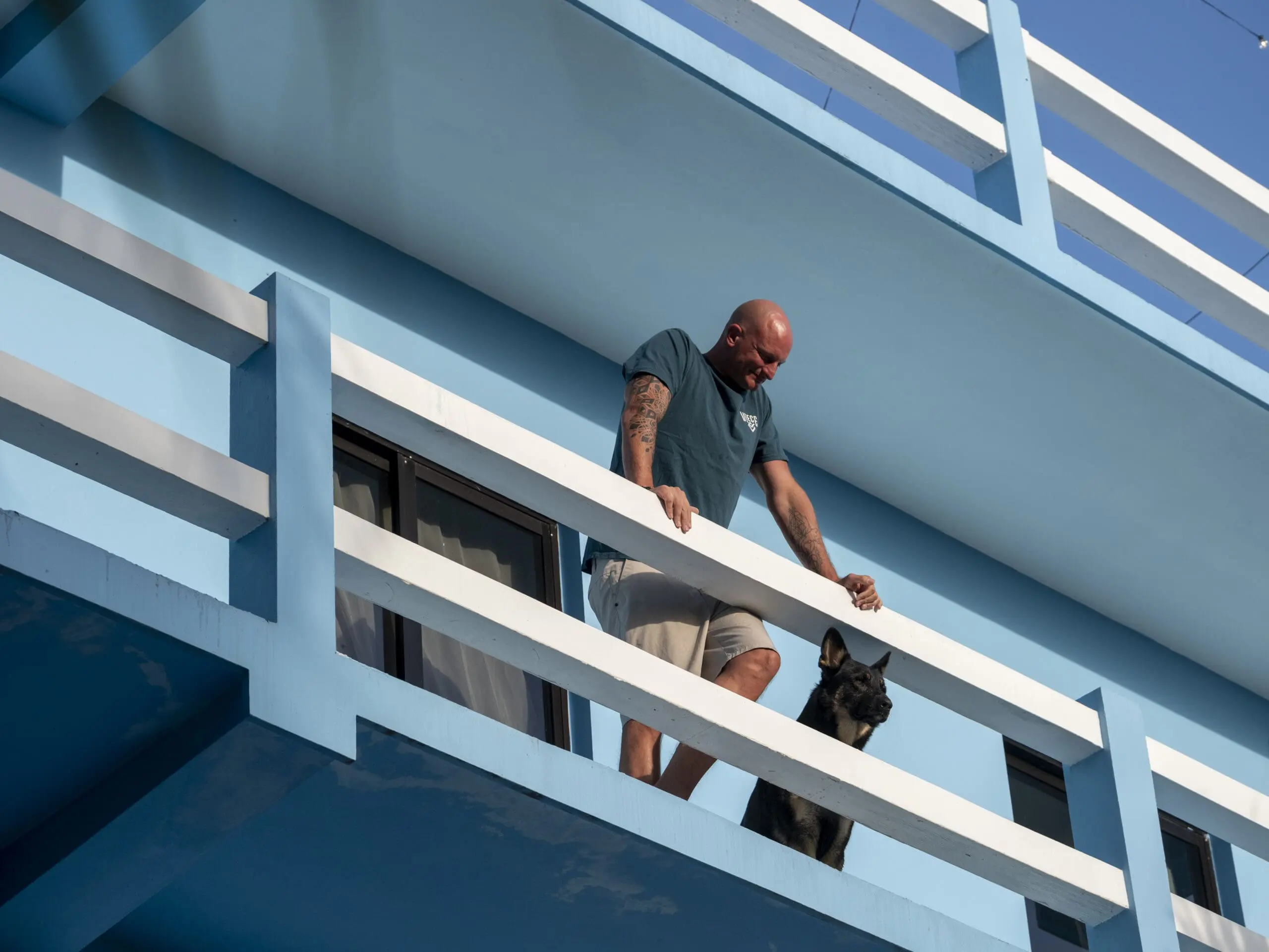 Man on balcony looking down with his german shepherd dog